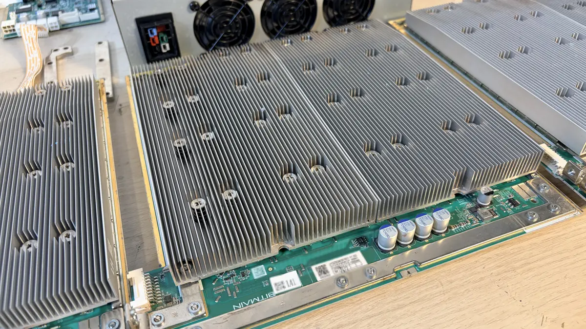 Placa hash del Antminer T21 en primer plano: los chips bajo los disipadores de aletas, los condensadores y los circuitos de alimentación en el borde de la placa