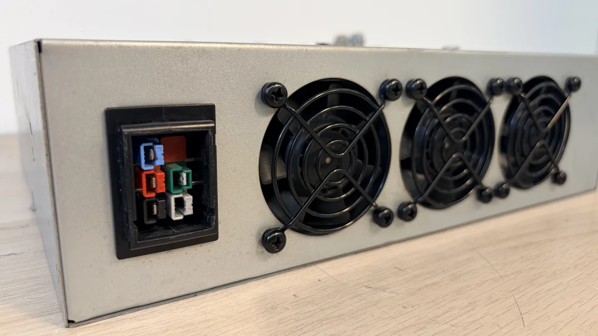 Parte trasera de la fuente de alimentación de un ASIC: bornera de entrada trifásica de cinco contactos y tres ventiladores de extracción